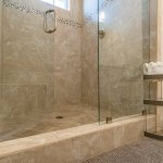Detail of frameless shower glass doors with brushed nickel hinges and hardware