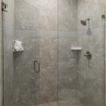 Frameless glass shower enclosure with door and stationary panel